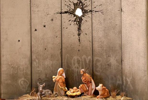 Nativity scene artwork against a concrete wall